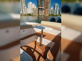 Interior view of a boat featuring a stylish seating area and table, perfect for relaxing while enjoying the waterfront scenery.