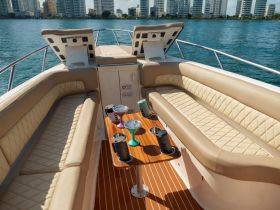 A stylish interior view of a boat's seating area, featuring comfortable cushions and a table set for drinks, perfect for relaxing on the water.