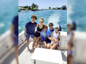 A joyful family poses together on a boat, enjoying a sunny day on the water — perfect for creating lasting memories during summer adventures.