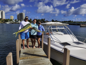 A group proudly displays their impressive catch of fish on the dock next to their boat, celebrating a successful fishing trip.