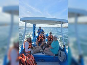 A cheerful group of friends enjoys a boat ride, all wearing life jackets, ready for an exciting day on the water.