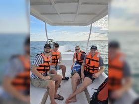 A cheerful group of friends enjoys a boat ride, all wearing life jackets for safety — perfect for adventure seekers and water enthusiasts.
