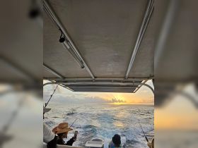 Guests enjoy a fishing trip at sunset, capturing the stunning ocean view while aboard a boat — a perfect blend of adventure and relaxation.