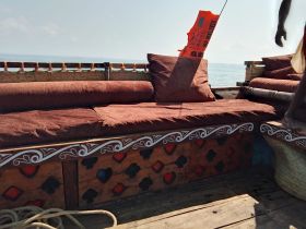 A cozy seating area inside a boat, featuring plush cushions and a scenic view of the water, perfect for relaxation during a maritime adventure.