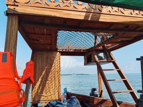 Interior view of a beautifully crafted wooden boat cabin, featuring a cozy seating area and decorative elements, perfect for relaxing while enjoying the water.