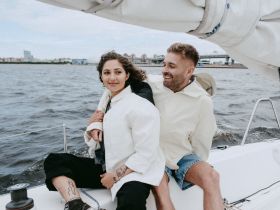 A joyful couple enjoys a sailing experience on the water, capturing a moment of happiness and connection amidst the scenic backdrop.