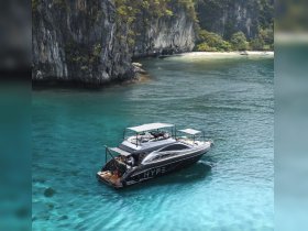 A stunning aerial view of a sleek yacht cruising through crystal-clear turquoise waters, surrounded by dramatic cliffs — perfect for luxury charters and scenic tours.