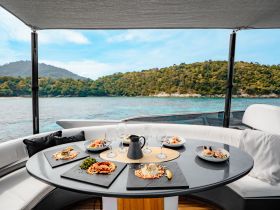 A beautifully arranged dining table on a yacht featuring gourmet dishes and cocktails, perfect for an upscale dining experience on the water.