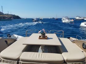 A cozy seating area on a boat featuring a table and decorative flowers, perfect for relaxing while enjoying the beautiful ocean views.