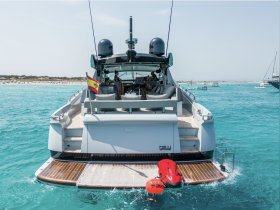 A stunning view of a luxurious yacht anchored in clear turquoise waters, showcasing its elegant design and inviting outdoor seating area.
