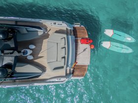 An aerial view of a luxurious boat deck featuring comfortable seating and water sports equipment, including paddleboards and a jet ski, perfect for a day of fun on the water.