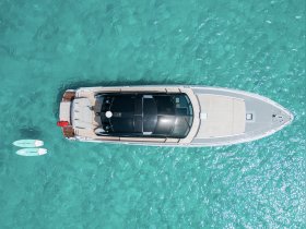 Aerial view of a sleek yacht cruising through crystal-clear waters, showcasing its elegant design and inviting deck space.