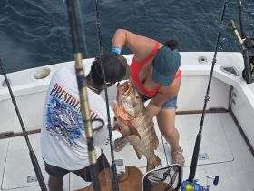 A thrilling moment on the water as two anglers celebrate their impressive catch while fishing aboard a boat — perfect for fishing enthusiasts and adventure seekers.