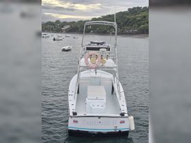 A clear view of the back of the 'Tantrum II' boat, docked in calm waters, showcasing its structure and design against a scenic backdrop.