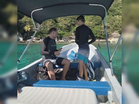 A man and a boy are inside a small boat, preparing for an adventure in clear turquoise waters, showcasing a cozy boat interior perfect for family outings.