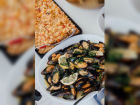 A delicious spread featuring fresh mussels garnished with lemon and herbs, alongside a vibrant rice dish — perfect for onboard dining experiences.