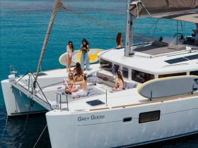 A lively group enjoys a sunny day aboard the yacht 'Grey Goose', relaxing and celebrating with drinks on the deck — perfect for summer outings and gatherings.