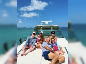 A joyful family enjoys a sunny day on the deck of a boat, creating lasting memories together in beautiful turquoise waters.