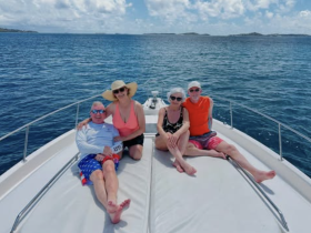A cheerful group enjoys sunbathing on the deck of a boat, surrounded by stunning ocean views — perfect for a relaxing day on the water.