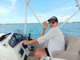 A joyful woman enjoys steering a boat, showcasing the fun of on-water activities and the thrill of boating adventures.