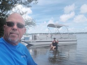 A man and a woman enjoy a relaxing day by the water, with the pontoon boat anchored nearby — perfect for a fun-filled day on the lake.
