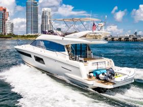 A stunning yacht named 'Whiskey & Waves' cruising through the waters of Miami Beach, showcasing its sleek design and vibrant surroundings.