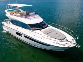 A stunning aerial view of a luxurious yacht cruising through clear waters, showcasing its elegant design and spacious deck — perfect for upscale boating experiences.