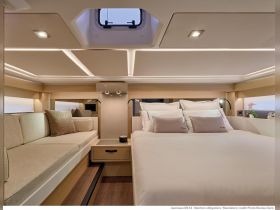 A beautifully designed interior of a Jeanneau DB 43, featuring a cozy lounge area and a comfortable sleeping space, perfect for relaxing on the water.