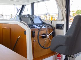 An interior view of a boat's helm featuring modern navigation equipment and comfortable seating, ideal for steering and managing the vessel.
