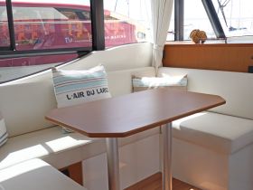 Cozy interior seating area of a boat featuring a stylish table and comfortable cushions, perfect for dining or relaxing while enjoying the views.