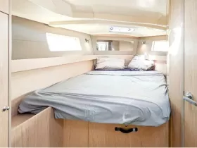 Cozy cabin interior featuring a comfortable bed and natural light, perfect for relaxing on a boat getaway.