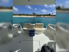 A cozy seating area inside a boat, featuring comfortable cushions and a cooler, perfect for relaxing while enjoying the beautiful views of the turquoise waters and sandy beach.