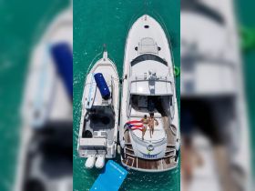 A couple relaxes on the deck of a yacht under the sun, surrounded by stunning turquoise waters — a perfect getaway for sunbathing and enjoying the sea.