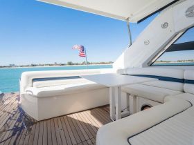 A stylish interior view of a boat's lounge area featuring comfortable seating and a table, perfect for relaxing while enjoying the scenic waterfront.
