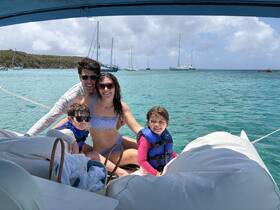 A joyful family enjoys a sunny day on the water, capturing a perfect moment aboard their boat with stunning turquoise waters in the background.