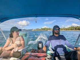 Two individuals enjoy a scenic boat ride, capturing the essence of adventure on the water with beautiful coastal views in the background.
