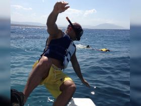 A snorkeler prepares to jump into the clear blue waters, ready for an underwater adventure — perfect for exploring vibrant marine life.