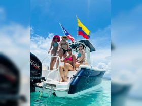 A fun group of friends poses on the steps of a boat, enjoying a sunny day on the water — perfect for memorable outings and celebrations.