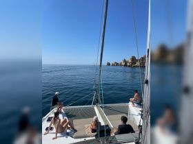 A group enjoys a relaxing day aboard a catamaran, soaking up the sun and taking in the stunning ocean views — perfect for a memorable sailing experience.