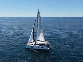 A stunning aerial view of a catamaran sailing smoothly across the open sea, showcasing its elegant design and the beauty of the surrounding waters.