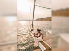 A couple enjoys a romantic moment aboard a yacht during sunset, creating the perfect backdrop for love and celebration on the water.
