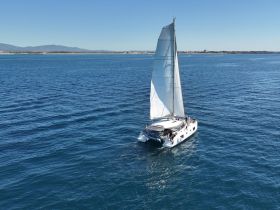 A stunning aerial view of a catamaran sailing through clear blue waters, showcasing the perfect setting for a day of adventure on the sea.