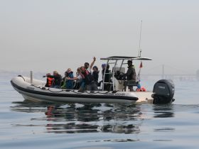 A lively group enjoys a day on the water, celebrating aboard a boat with smiles and waves, perfect for unforgettable adventures.