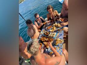 A lively group enjoys a delicious spread of snacks while relaxing on a boat, perfect for a fun day on the water with friends.