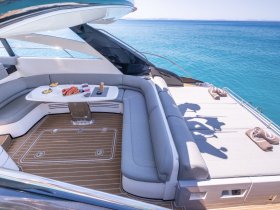 A beautifully designed interior seating area on a luxury yacht, featuring a dining table set with fresh fruits and snacks, perfect for relaxing and enjoying the ocean views.