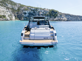A stunning view of a luxury yacht named 'Make My Day' docked in crystal-clear waters, surrounded by picturesque cliffs — perfect for a serene getaway.