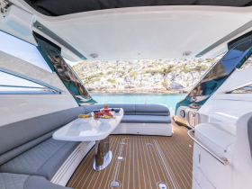 A stylish interior view of a boat's dining area featuring comfortable seating and a table set with snacks, perfect for enjoying meals while cruising.