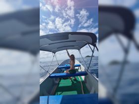 A joyful individual enjoys a sunny day on a boat, waving with excitement — a perfect snapshot of fun on the water.