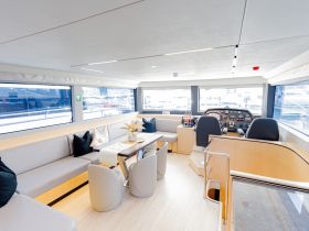 A spacious and modern interior of a boat featuring comfortable seating and a well-equipped helm, perfect for relaxing or navigating on the water.