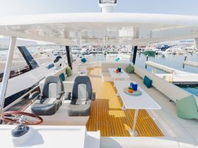 A spacious and stylish interior of a yacht featuring comfortable seating and a helm, perfect for relaxing or navigating the waters.
